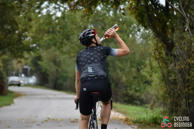 Cyclists drinking from wine bottle while on a bike